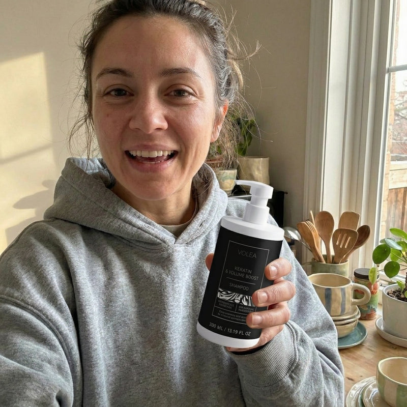 Person holding a bottle of Volta shampoo product in a home setting